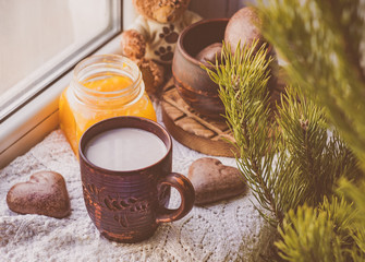 A mug of cocoa and heart-shaped cookies on a windowsill in the morning