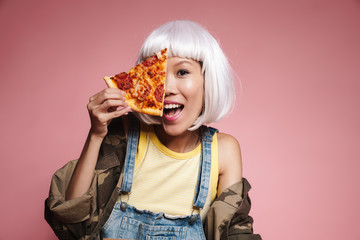 Image of young asian girl wearing white wig having fun and eating pizza