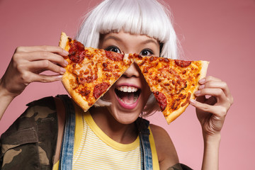 Image of young asian girl wearing white wig having fun and eating pizza