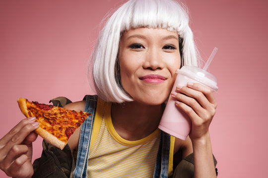 Image of asian girl in white wig drinking milkshake and eating pizza