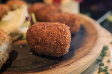 Wooden plate with croquettes, typical Spanish, with soft sun light and unfocused background