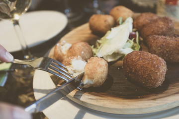 Plate of food and glasses of wine during a meal of friends. Several croquettes placed on a wooden...