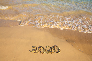 2020 summer beach holiday season written on golden sand washed away wave - new season lettering on sand - numbers 2020 year travel vacation sandy wavy water yellow blue azure aquamarine turquoise