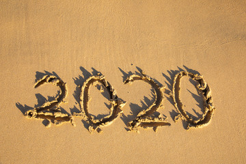 2020 summer beach holiday season written on golden sand - new season lettering on sand - numbers 2020 year travel vacation sandy yellow