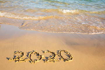 2020 summer beach holiday season written on golden sand washed away wave - new season lettering on sand - numbers 2020 year travel vacation sandy wavy water yellow blue azure aquamarine turquoise