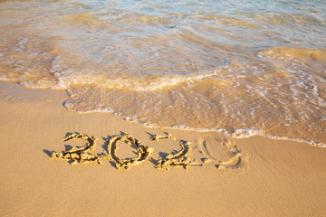 2020 summer beach holiday season written on golden sand washed away wave - new season lettering on sand - numbers 2020 year travel vacation sandy wavy water yellow blue azure aquamarine turquoise