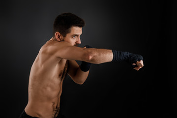 Naklejka na ściany i meble Sportsman boxer throwing a fierce and powerful punch. muscular man on black background.