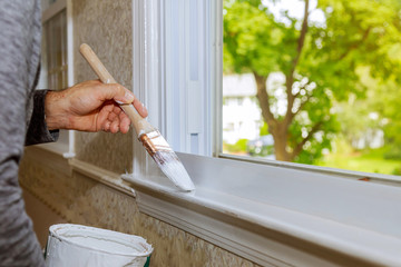 Hand with paintbrush painting a window white