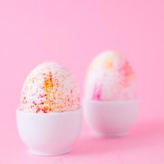 Two easter eggs decorated with watercolour aquarelle, minimalism style on plain pink background. Easter holiday decorations with copy space