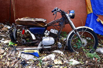 Old, broken and rusty motorcycle at an empty lot