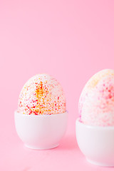 Two easter eggs decorated with watercolour aquarelle, minimalism style on plain pink background. Easter holiday decorations with copy space