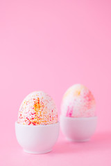 Two easter eggs decorated with watercolour aquarelle, minimalism style on plain pink background. Easter holiday decorations with copy space