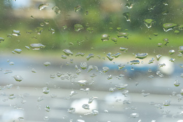 Rains droplet on a glass with clouds and building background.