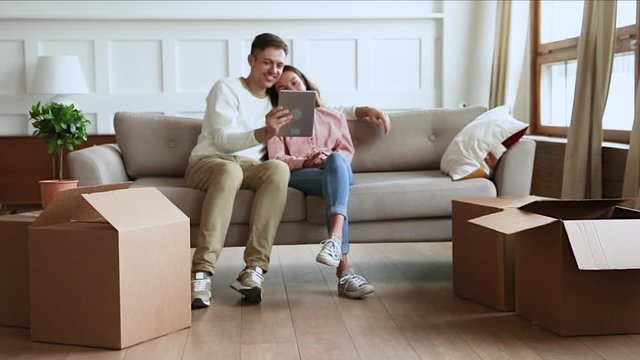 Children playing with boxes parents using tablet on moving day