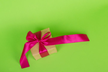 Womans day concept. Gift box wrapped in craft paper. gift with a pink ribbon on a green background.
