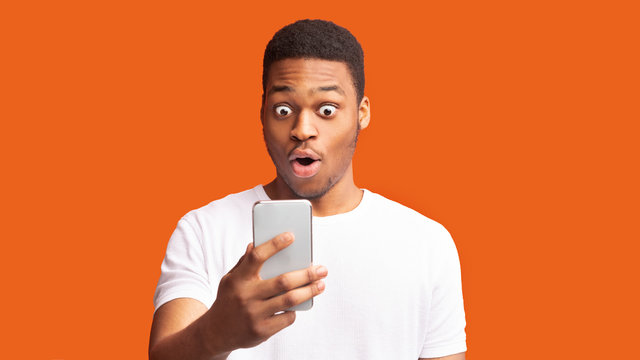 Closeup portrait of surprised african guy looking at phone