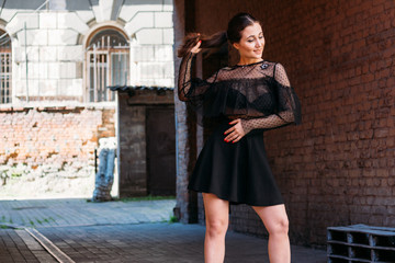 the girl is posing smiles. Emotional portrait of Fashion stylish portrait of pretty young woman. city portrait. brunette in a black dress with stars and planets on a dress. expectation. dreams