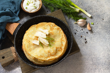 Stack Potato pancakes, not sweet, served with garlic cream sauce on a gray stone background. Copy space.