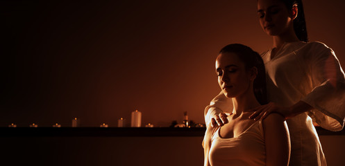 Young fit woman has Thai massage at luxury spa. Warm inviting colors, calm atmosphere, charming light. Copy space