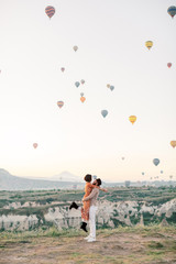 Woman and man watching colorful hot air balloons flying over the valley at Cappadocia, Turkey.Turkey Cappadocia fairytale scenery of mountains. Turkey Cappadocia fairytale scenery of mountains