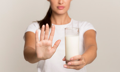 Unrecognizable Lady Holding Milk Gesturing No To Glass, Gray Background