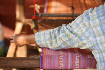 Fototapeta premium Weaving. Woman hand weaving on manual loom. Fabric handmade. Homespun fabric process. The process of fabric weaving in vintage weaver machine. Selective focus.