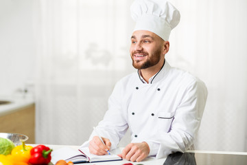 Chef Man Writing Recipes Working On Culinary Book In Kitchen