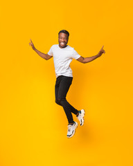 Obraz premium Afro Man Having Fun Jumping In Air Over Yellow Background