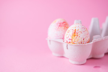 Two easter eggs decorated with watercolour aquarelle splash, minimalism style on plain pink background. Easter holiday decorations with copy space