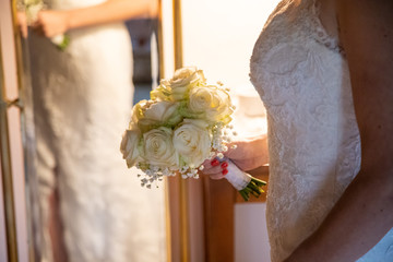 Détail de la robe de la marié avec son bouquet le jour de son mariage