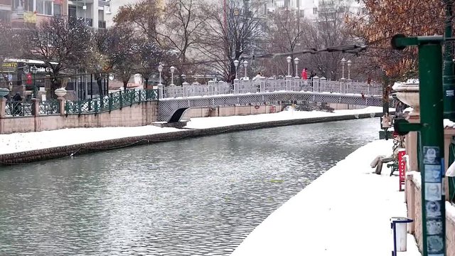 Beautiful Snow Landscape of Porsuk River with bridge and trees at the background in Winter season, in Eskisehir, Turkey. Beautiful view of snow in city center.