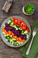 Vegetable cobs salad with stamates, cucumber, pepper, spinach and olive sauce on a wooden background. Salad is a rainbow.