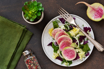 Salad with spinach, cabbage and radish on a rustic, concrete background. Proper nutrition.