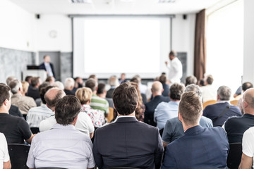 I have a question. Group of business people sitting at the chairs in conference hall. Businessman...