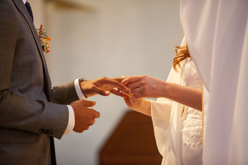 Mariés qui se passent la bague au doigt le jour du mariage dans l'église