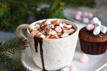Hot chocolate with marshmallows and muffin on a concrete background.