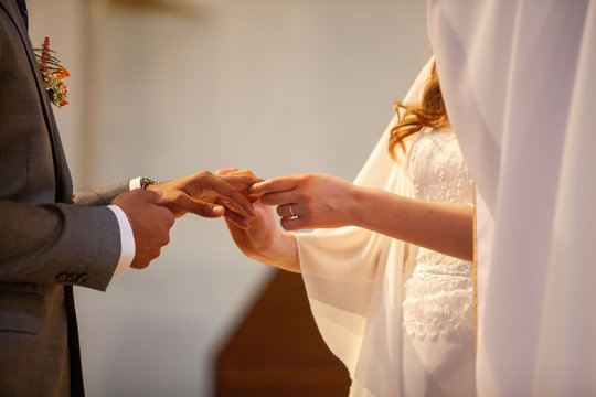 Mariés qui se passent la bague au doigt le jour du mariage dans l'église