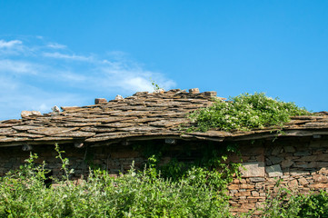 Old rural country stone house facade in sunny summer day