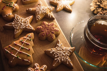 Christmas homemade gingerbread cookies on cutting board with cup of tea on table