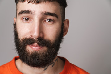 Fototapeta premium Image of young bearded man with nose jewelry wearing orange shirt