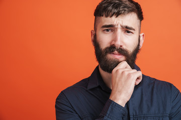 Image of serious man with nose jewelry thinking and touching his chin