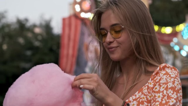 A beautiful woman is eating candyfloss in amusement park