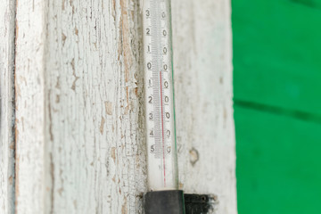 Old outdoor thermometer on a wooden house with zero degrees
