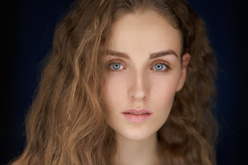 close-up portrait of beautiful woman with long curly blond hair on black background