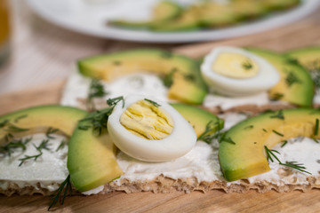 Avocado toast with egg whites and pea shoots, orange juice on wooden board, overhead view