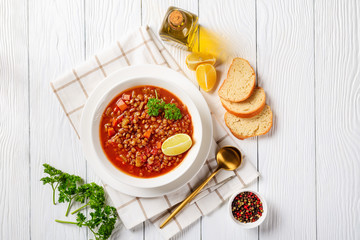 lentil soup with vegetables and lemon wedges