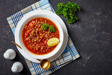 lentil soup with vegetables and a lemon wedge