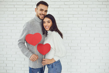 Concert Valentine's Day. Young couple with hearts in hands on a white brick background