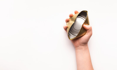 Woman hand holds a crumpled tin can on a white
