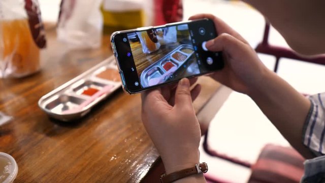Close-up of women hands with a phone while she takes a photo of her food